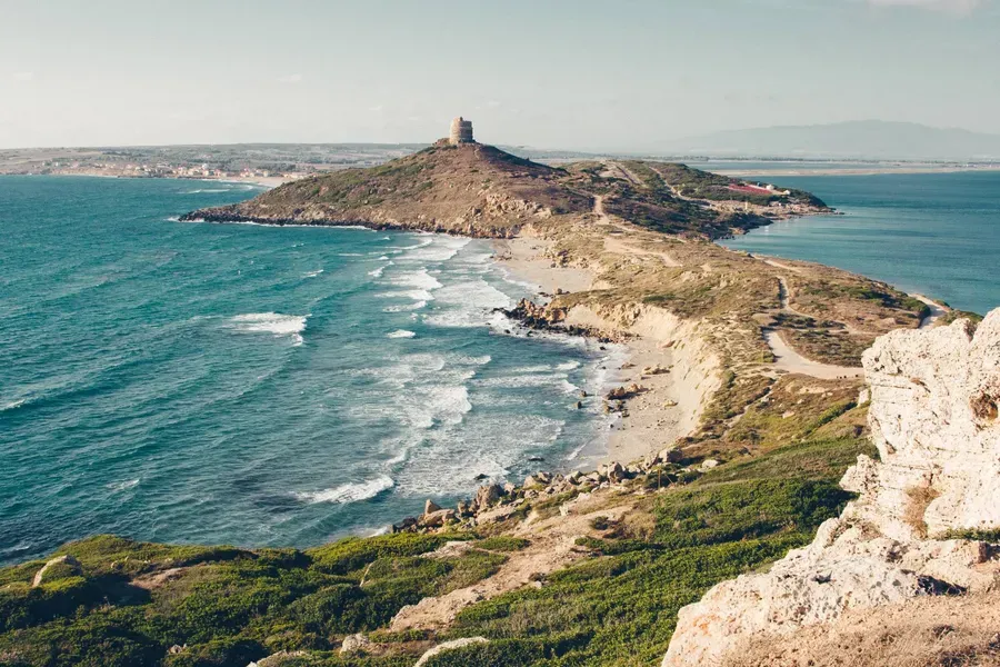 Costa do Mediterrâneo com mar azul, praia e torre antiga no alto do promontório